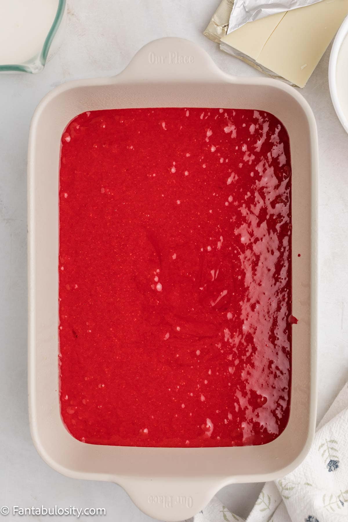 Red velvet cake batter spread in a 9x13 baking pan before baking.
