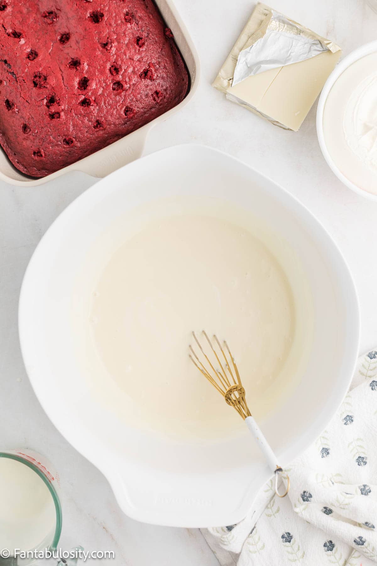 Sweetened condensed milk and heavy whipping cream whisked together in a white mixing bowl.