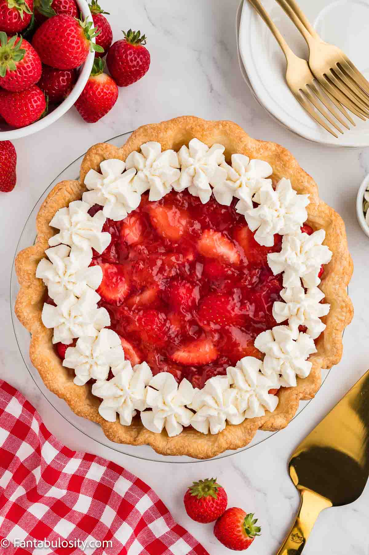 Fresh strawberry pie topped with piped whipped cream around the edge.