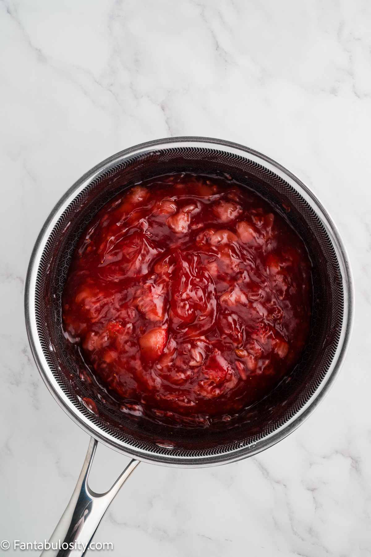 Thickened strawberry glaze in a saucepan after boiling.