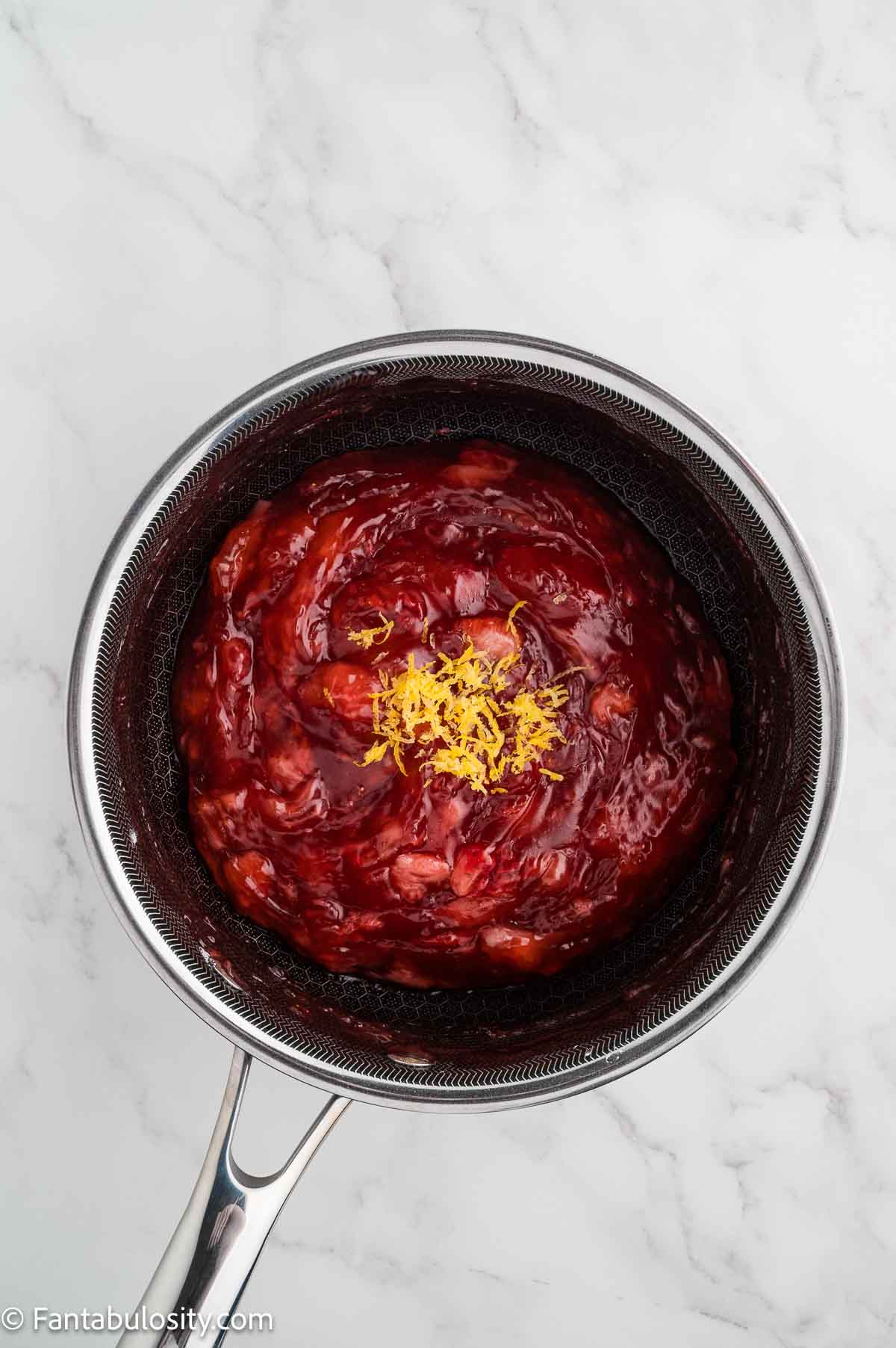 Lemon zest on top of the cooked strawberry glaze.