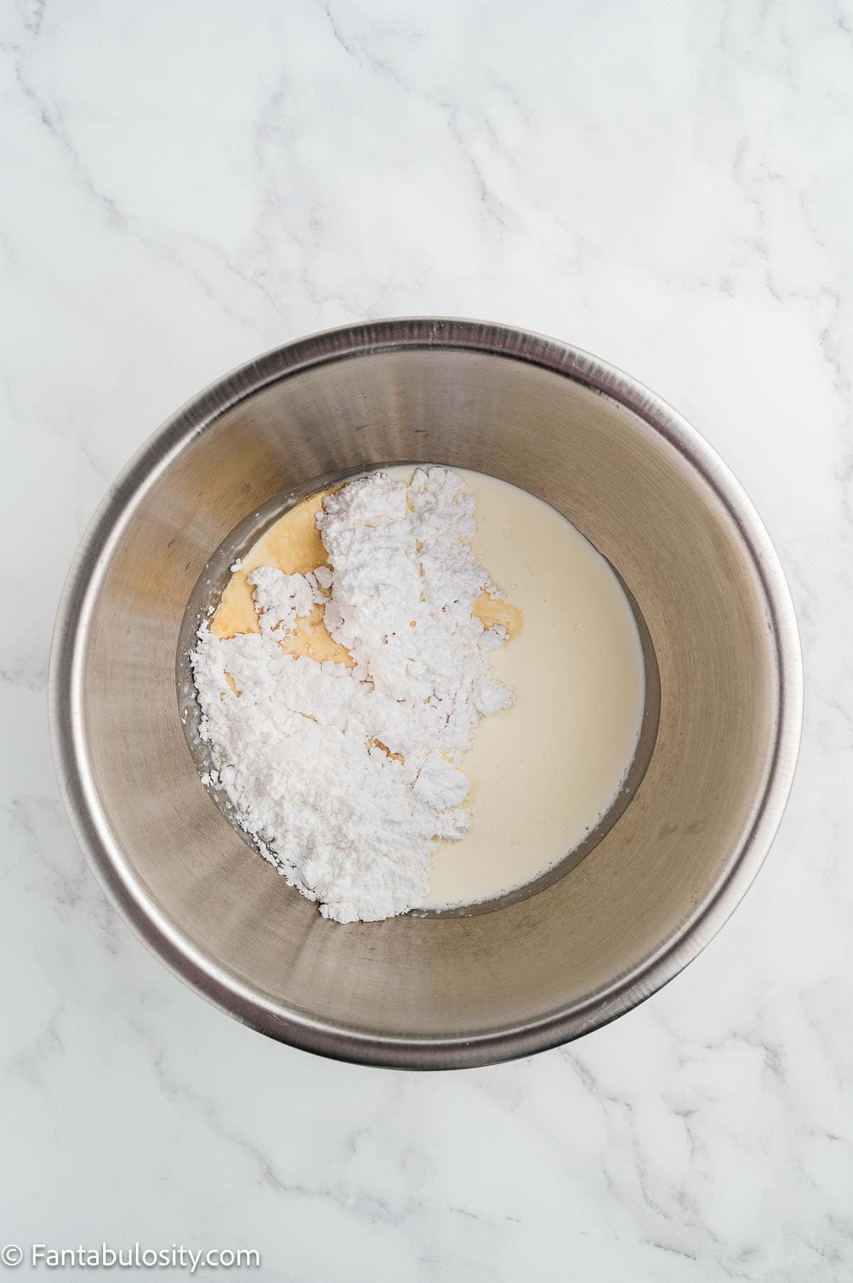 Heavy cream, vanilla, and powdered sugar in a mixing bowl.