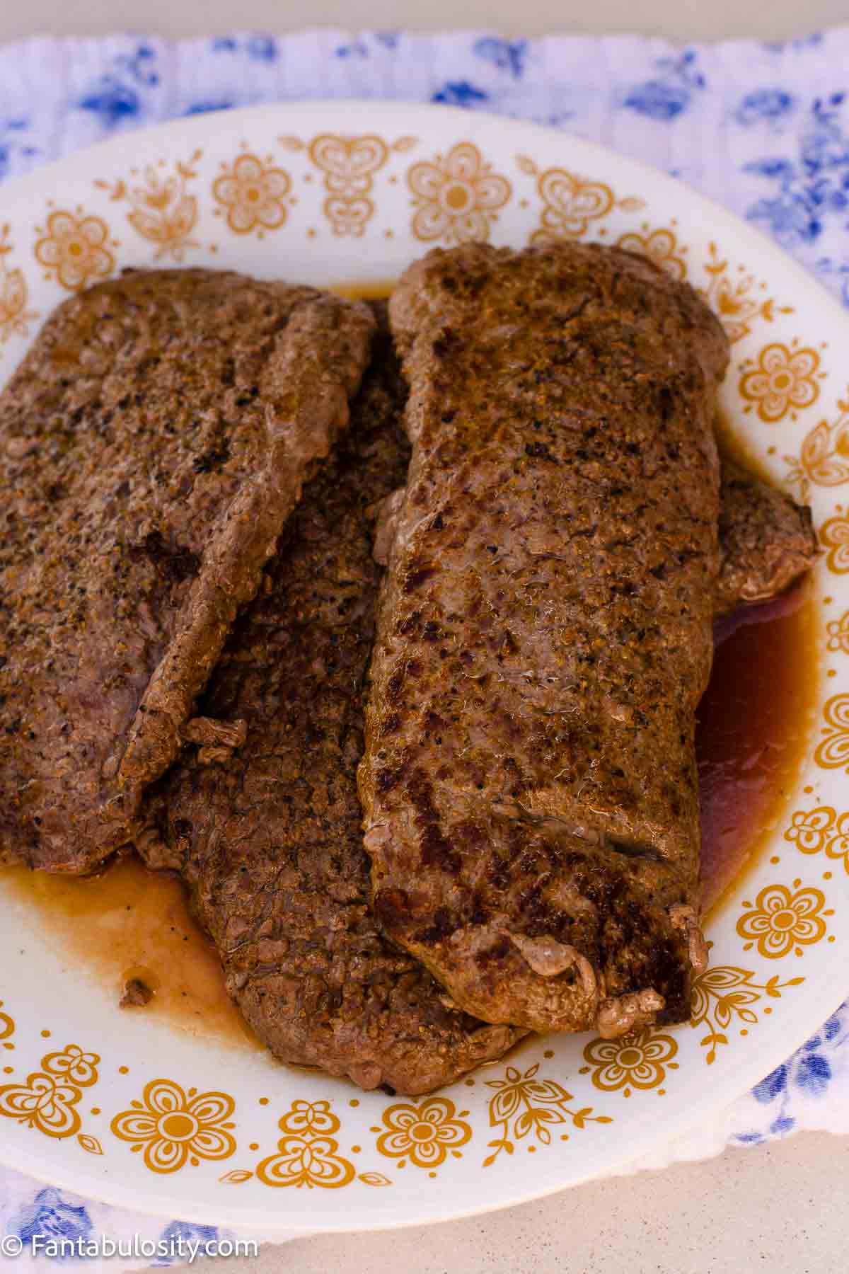 Two browned cube steaks resting on a floral plate.