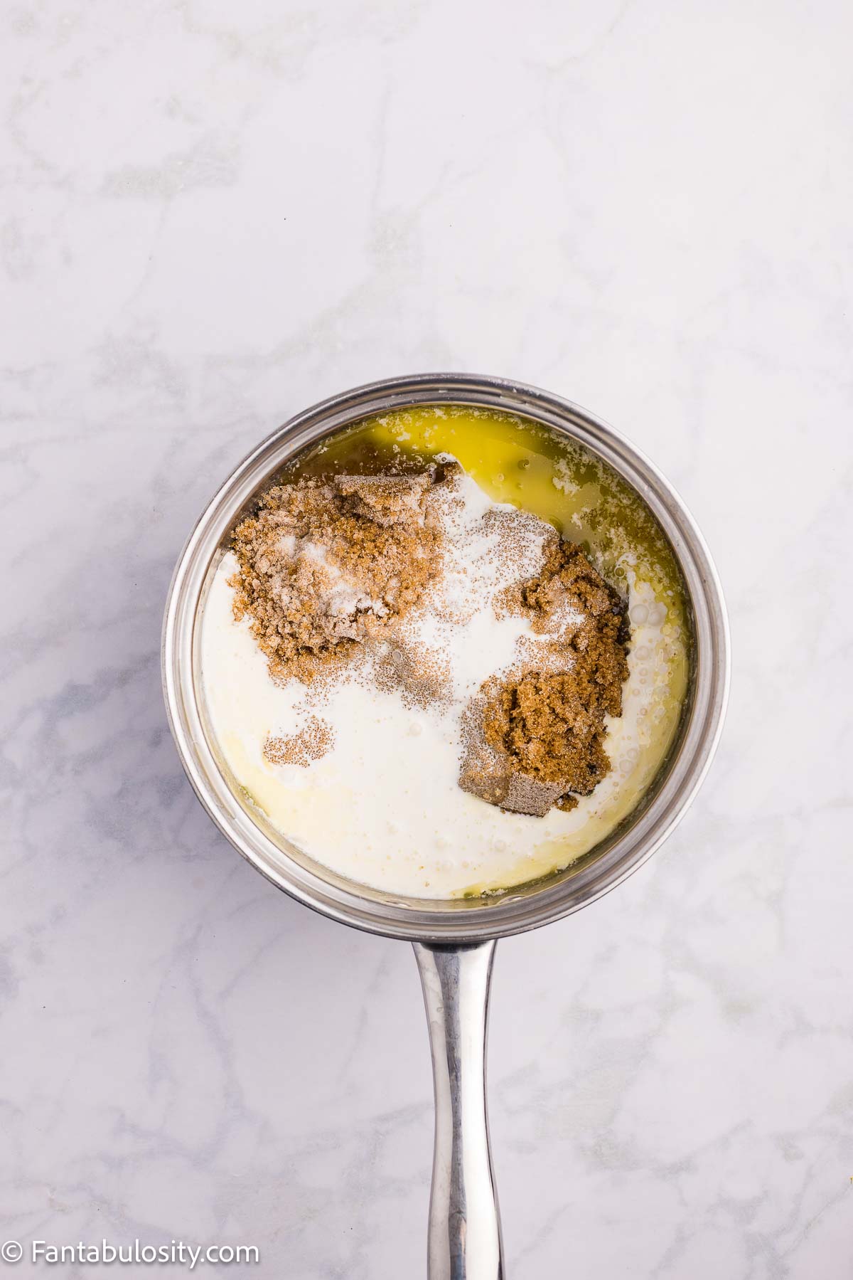 Brown sugar, granulated sugar and cream added to melted butter in a saucepan.