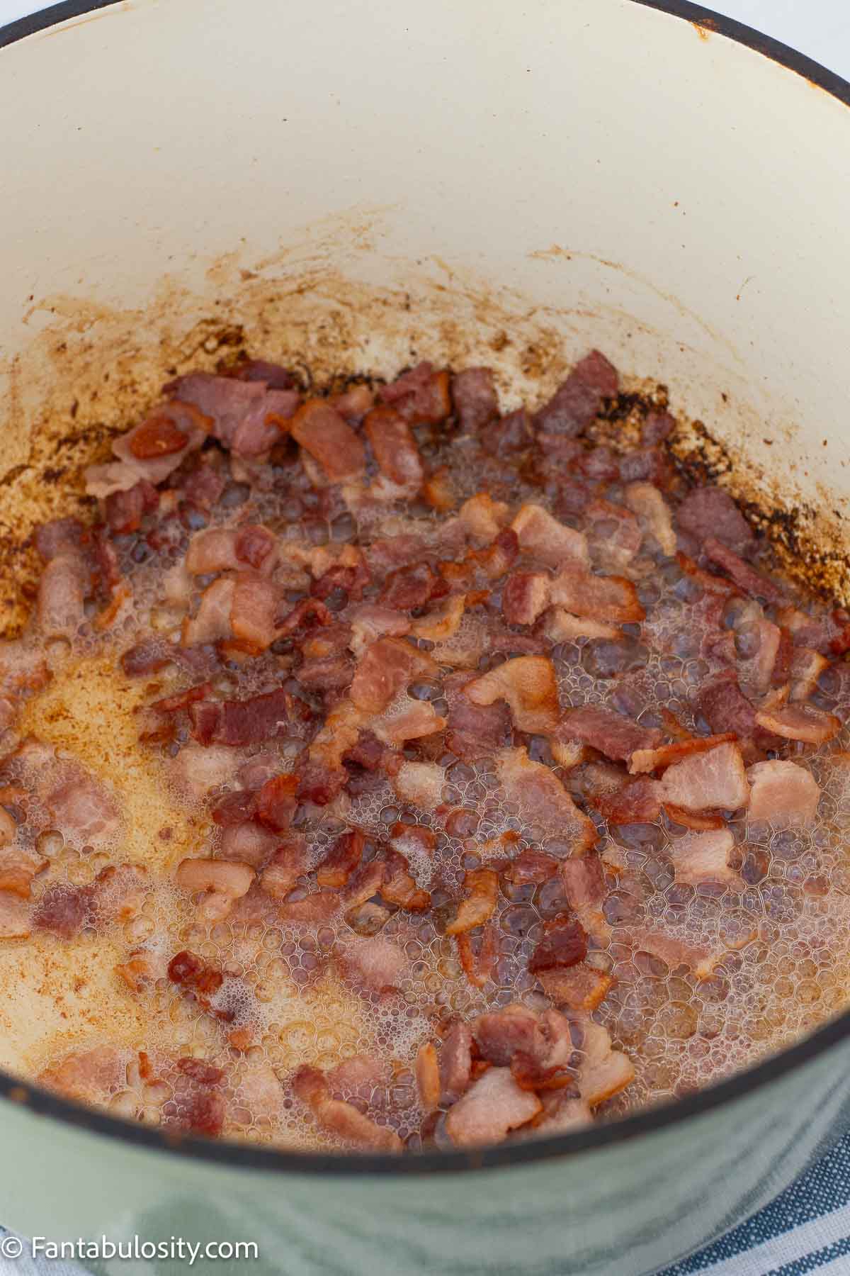 Chopped bacon cooking in a Dutch oven.