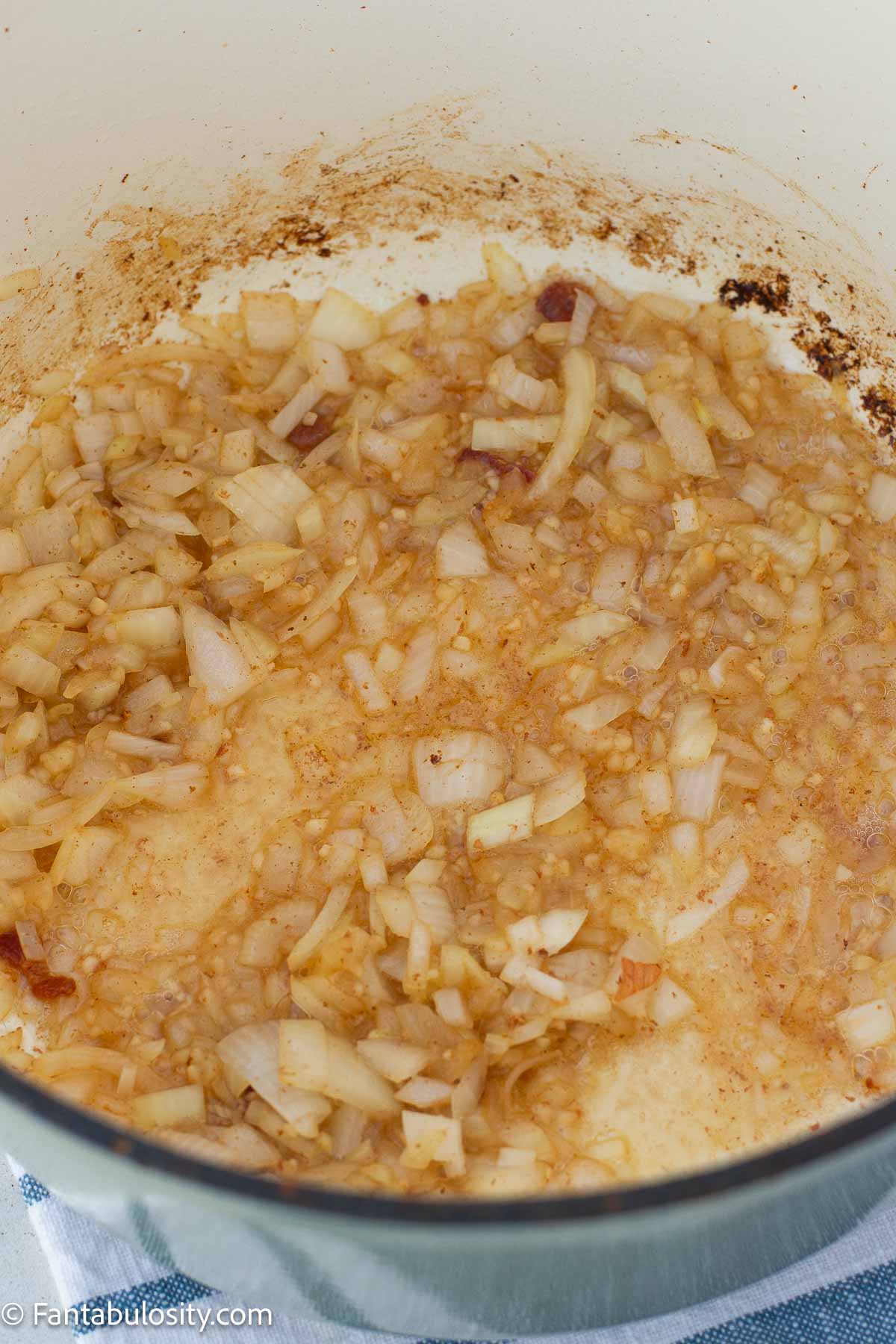 Diced onion cooking in bacon drippings in a Dutch oven.