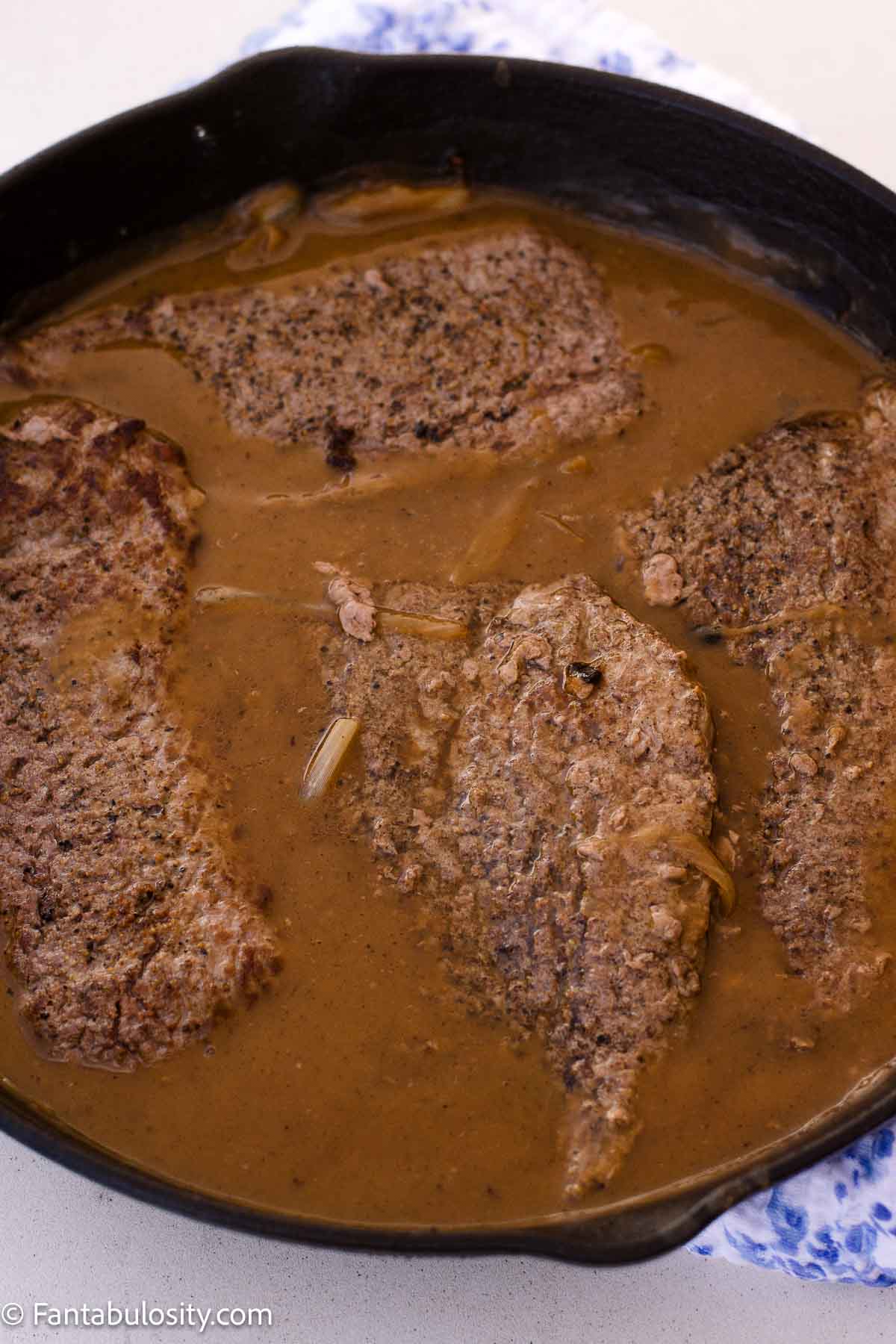 Browned cube steaks returned to the skillet of onion gravy.