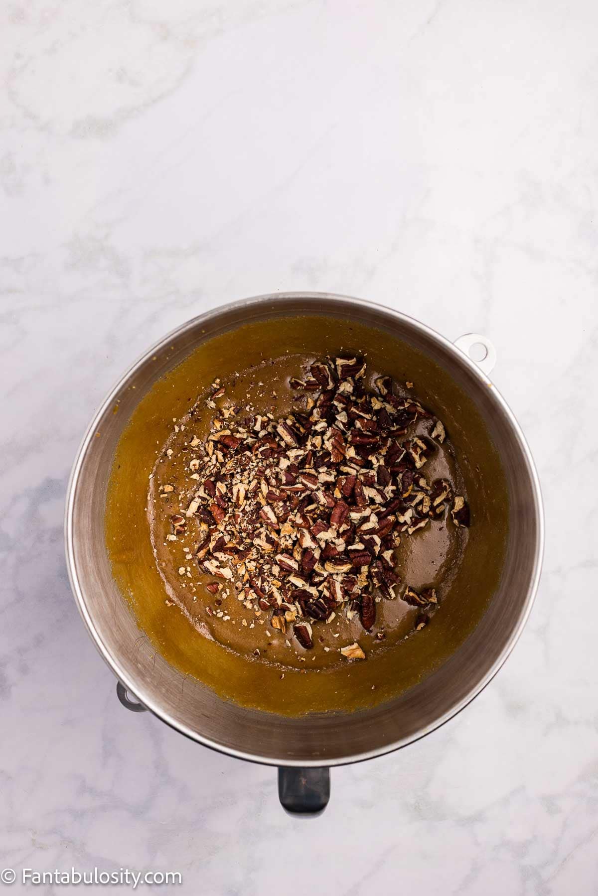 Chopped pecans added to the brown sugar fudge mixture in a mixing bowl.