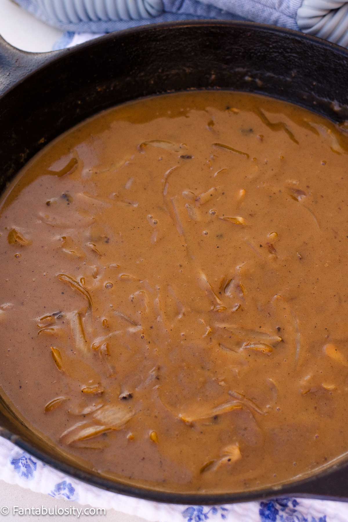 Brown onion gravy in a cast-iron skillet.