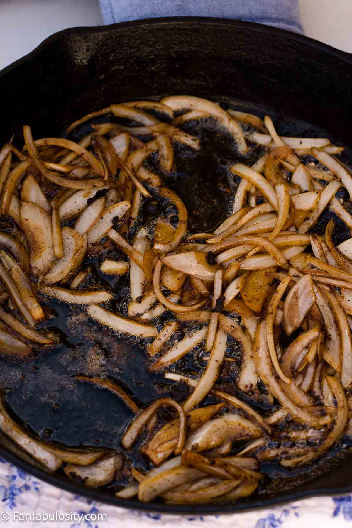 Sliced onions cooking in a cast-iron skillet.
