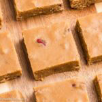 Penuche fudge squares with pecans on a wooden board.