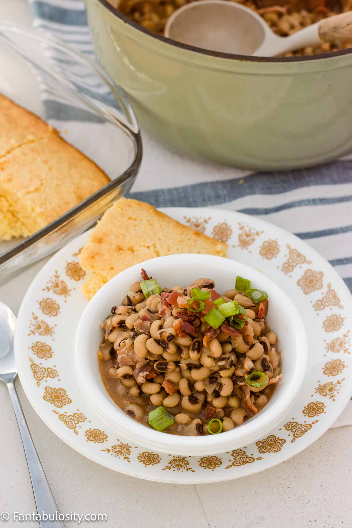 Black eyed peas served with cornbread, with a Dutch oven of peas in the background.