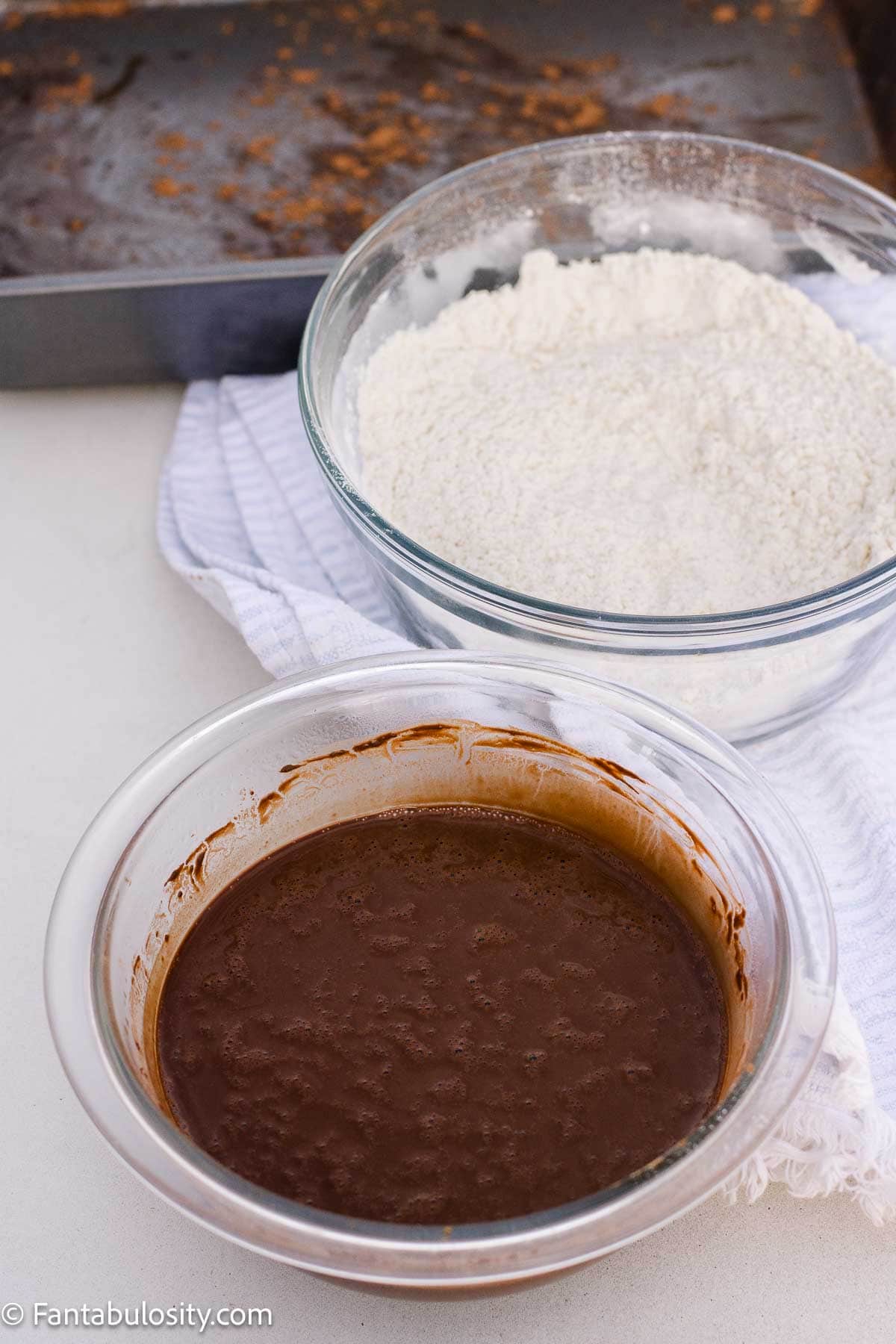 Bowl of flour next to a bowl of bloomed cocoa for chocolate mayonnaise cake.