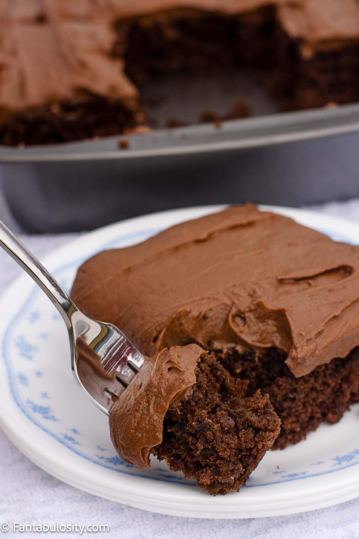 Slice of chocolate mayonnaise cake with chocolate buttercream frosting and a bite on a fork.