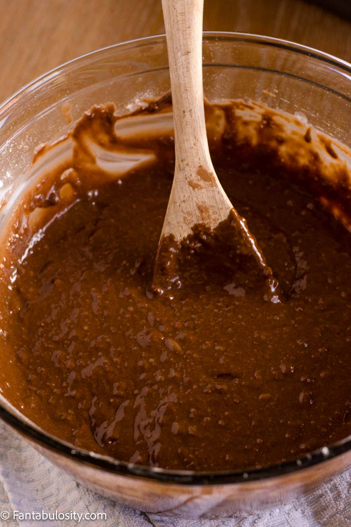 Chocolate mayonnaise cake batter stirred smooth with a wooden spoon.