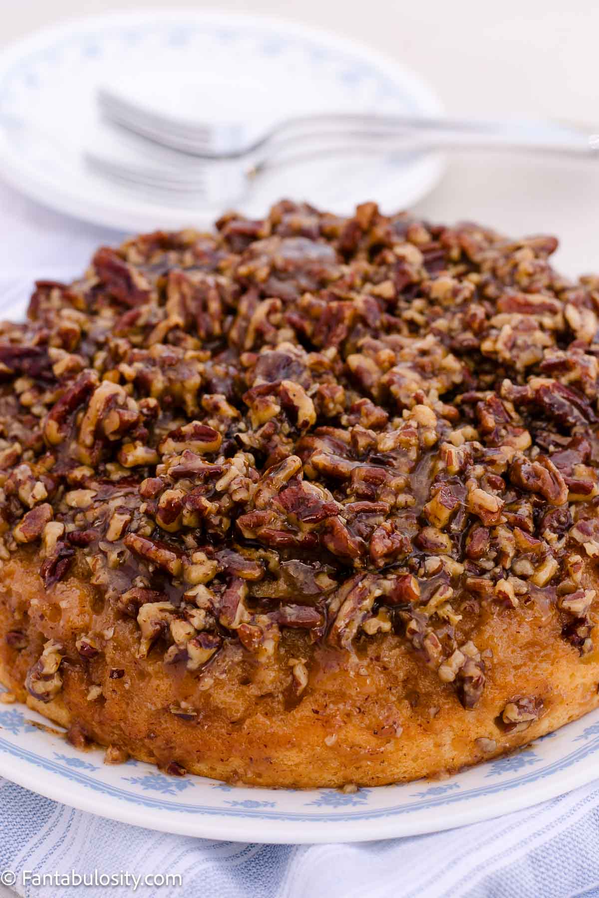 Pecan upside down cake on a blue and white serving plate
