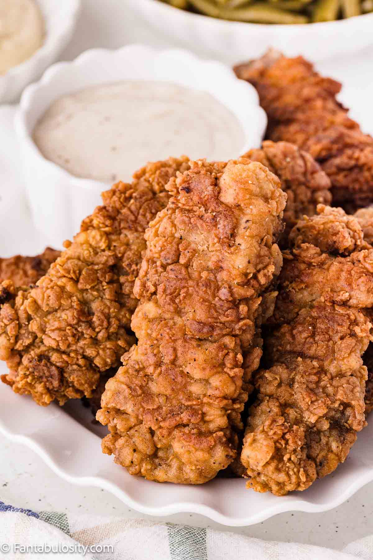 Golden steak fingers with a crisp coating, served beside white gravy.