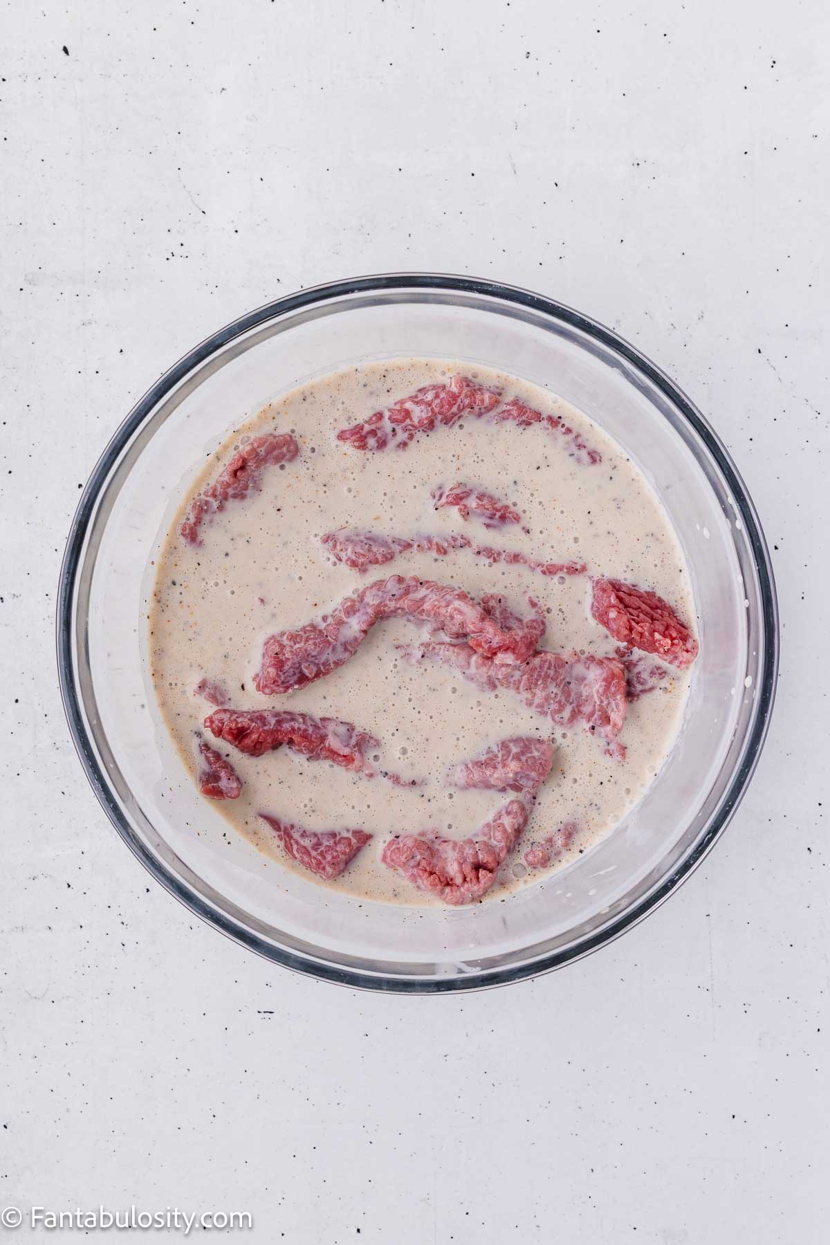 Cube steak strips in a seasoned buttermilk marinade.