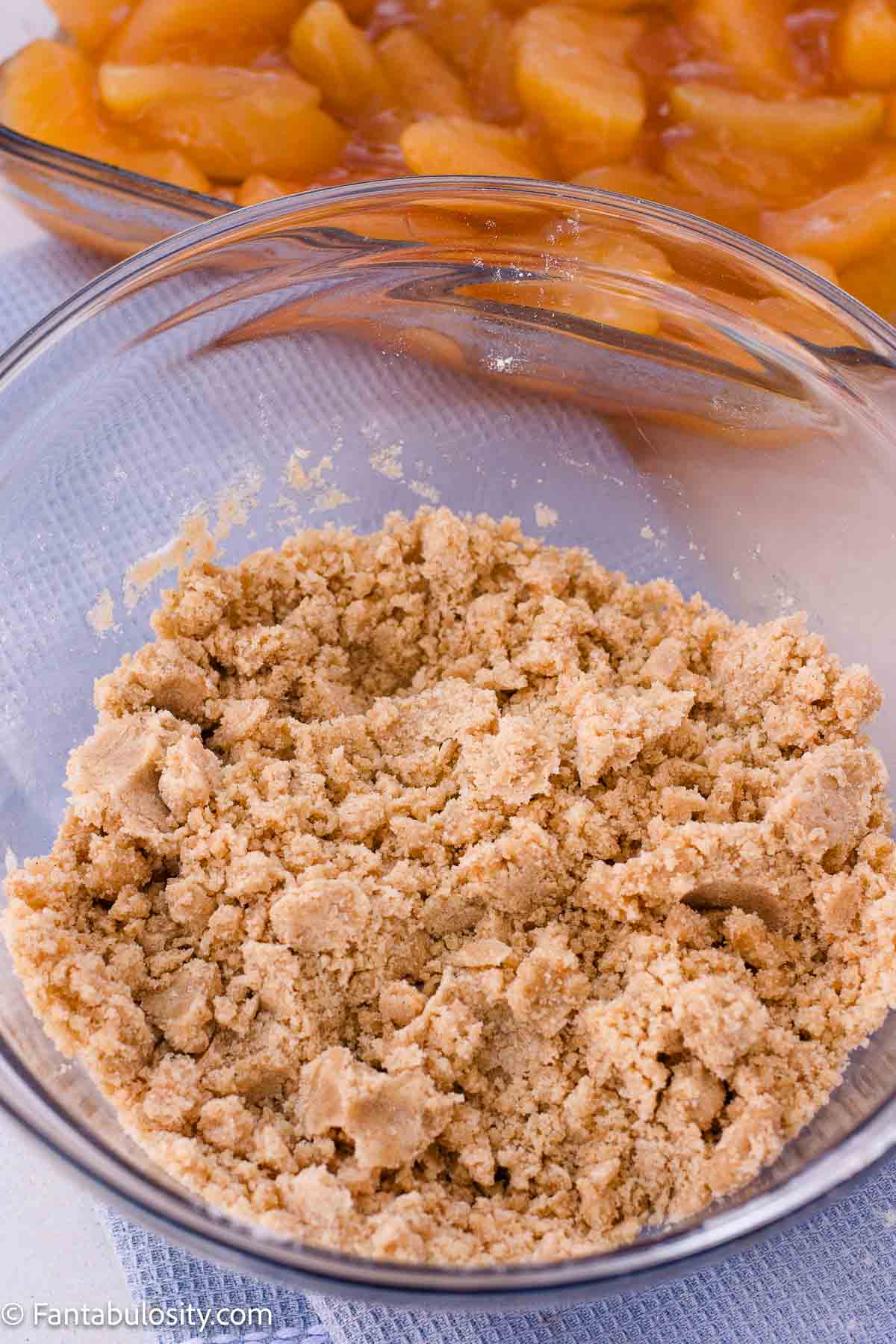 Buttery crumble topping mixed into small crumbs and larger clumps in a glass bowl.