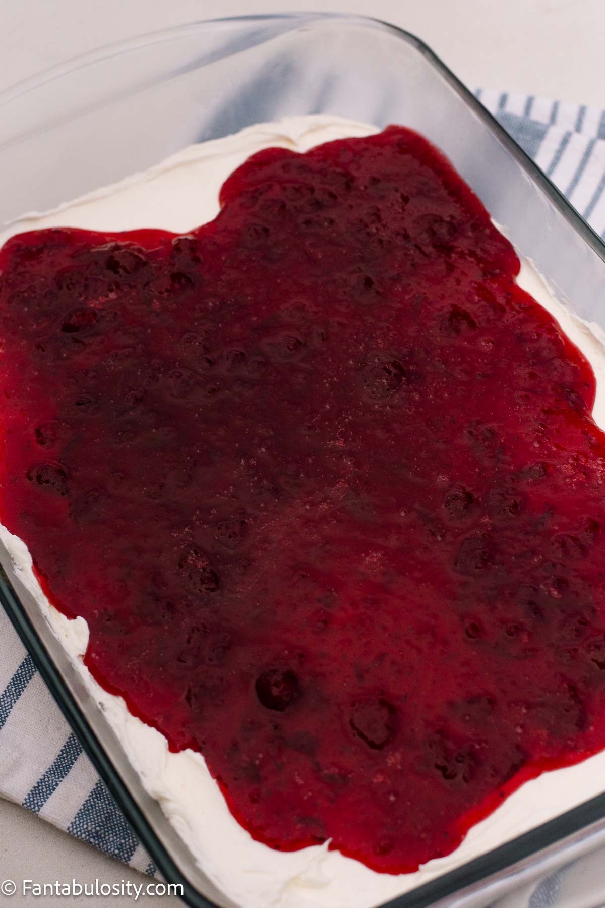 Cranberry mixture partially spread over the cream cheese layer in a glass dish.