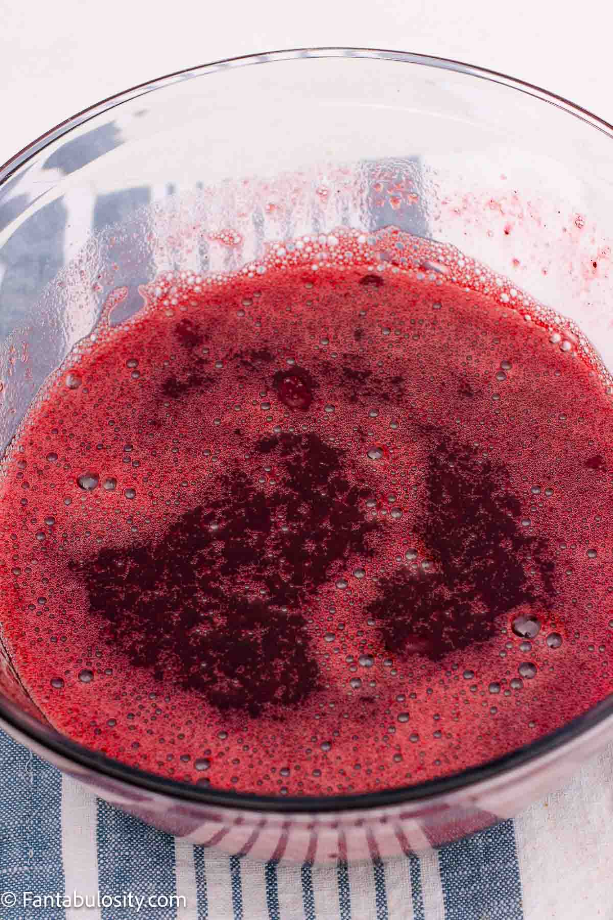 Cranberry gelatin and whole berry cranberry sauce mixed in a clear bowl.