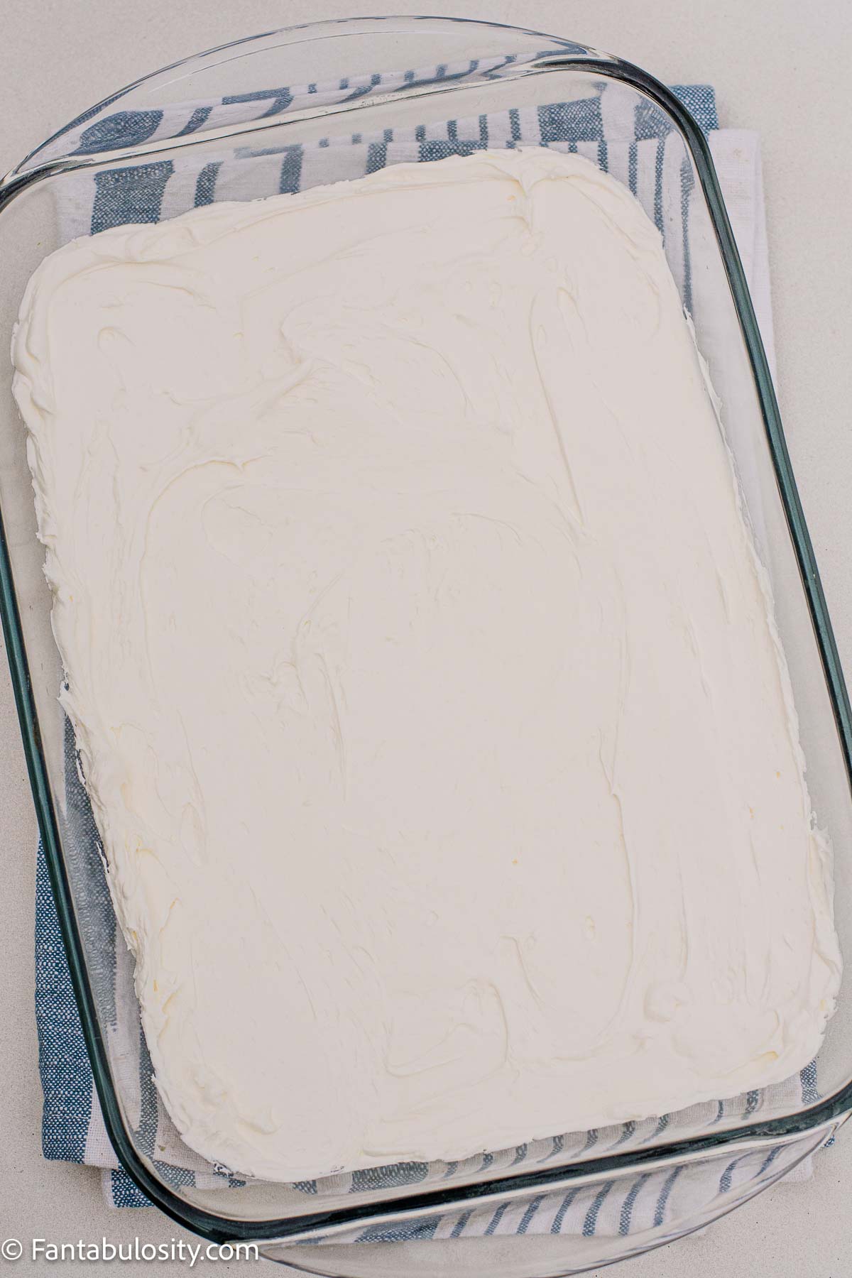 White cream cheese filling spread over the pretzel crust to the edges of a glass dish.