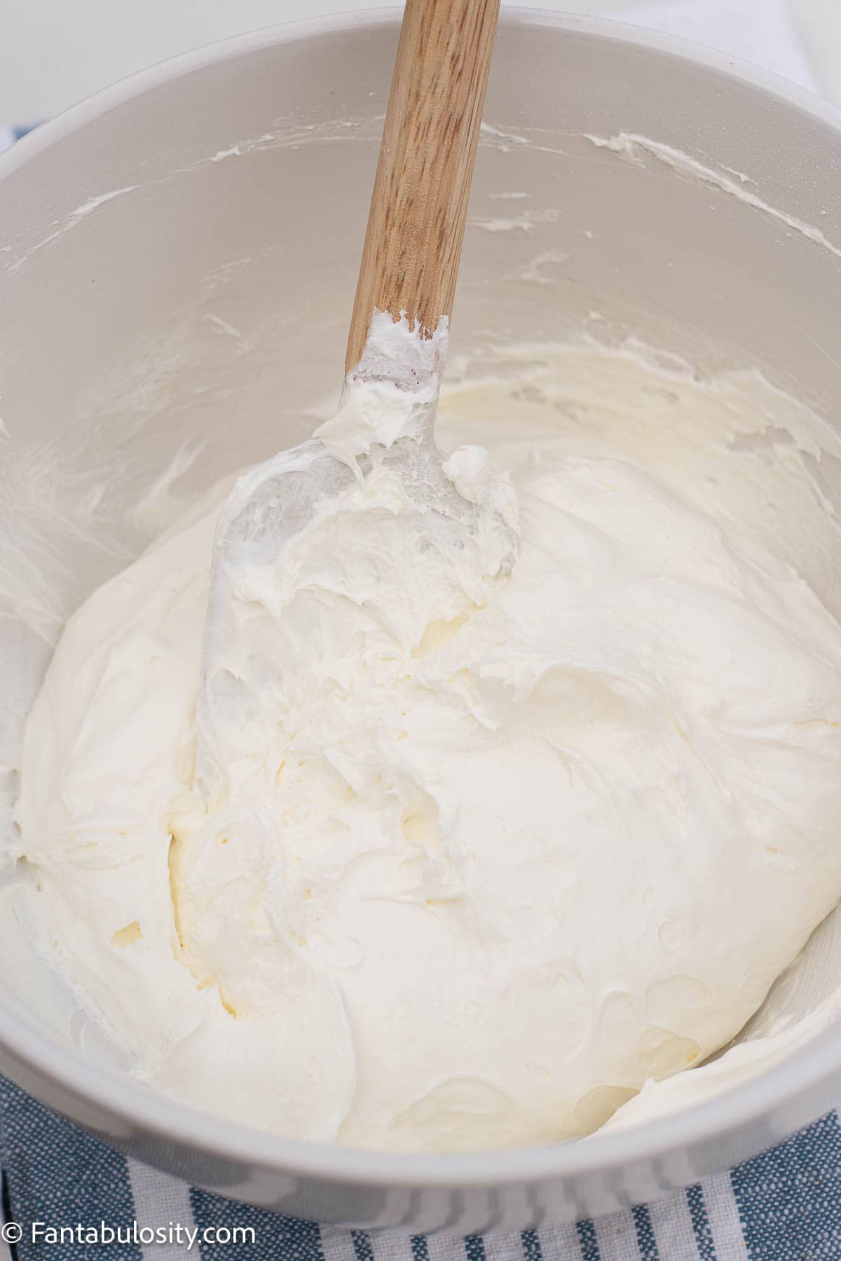 Cream cheese filling in a white mixing bowl with a spatula.