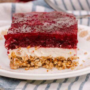 Close-up of the cranberry, cream cheese, and crumbly pretzel layers in a slice of cranberry pretzel salad.