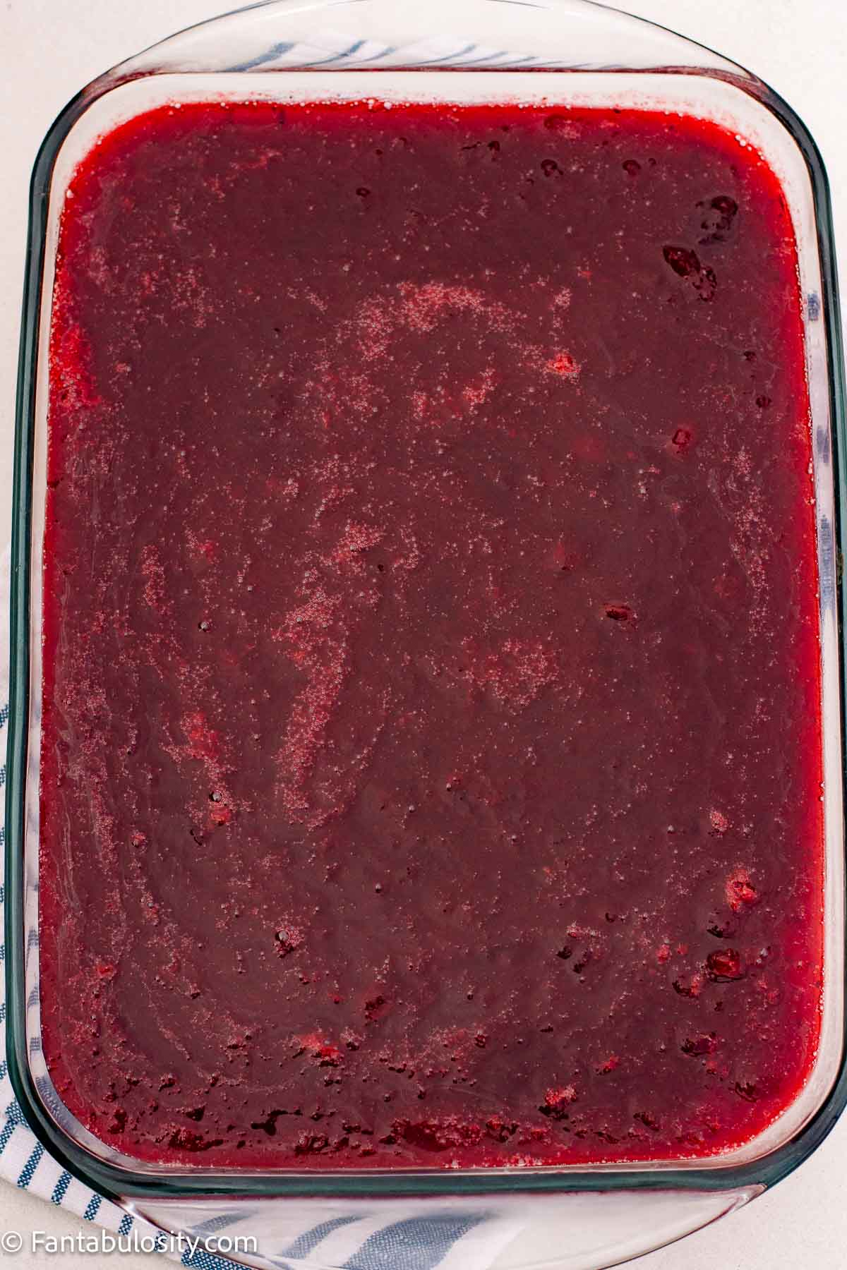 An overhead view of cranberry pretzel salad with the red topping spread across the pan.