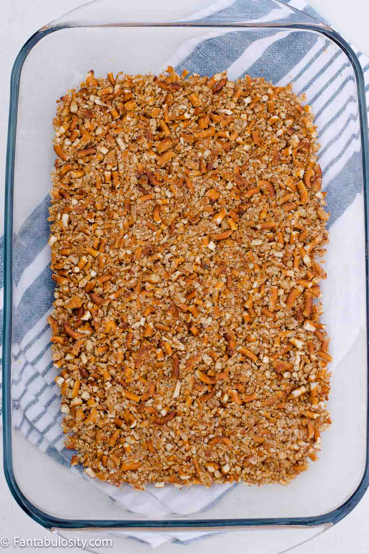Pretzel crumb mixture pressed into the bottom of a rectangular glass baking dish.