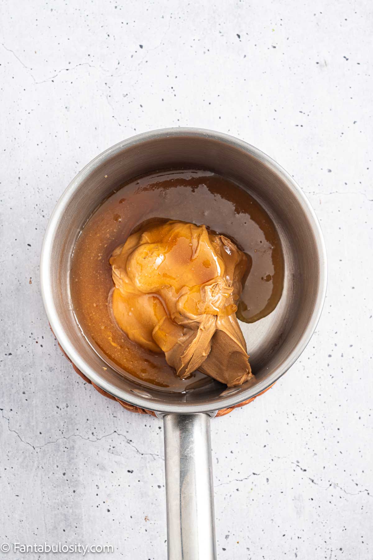 Creamy peanut butter and honey in a saucepan before warming.