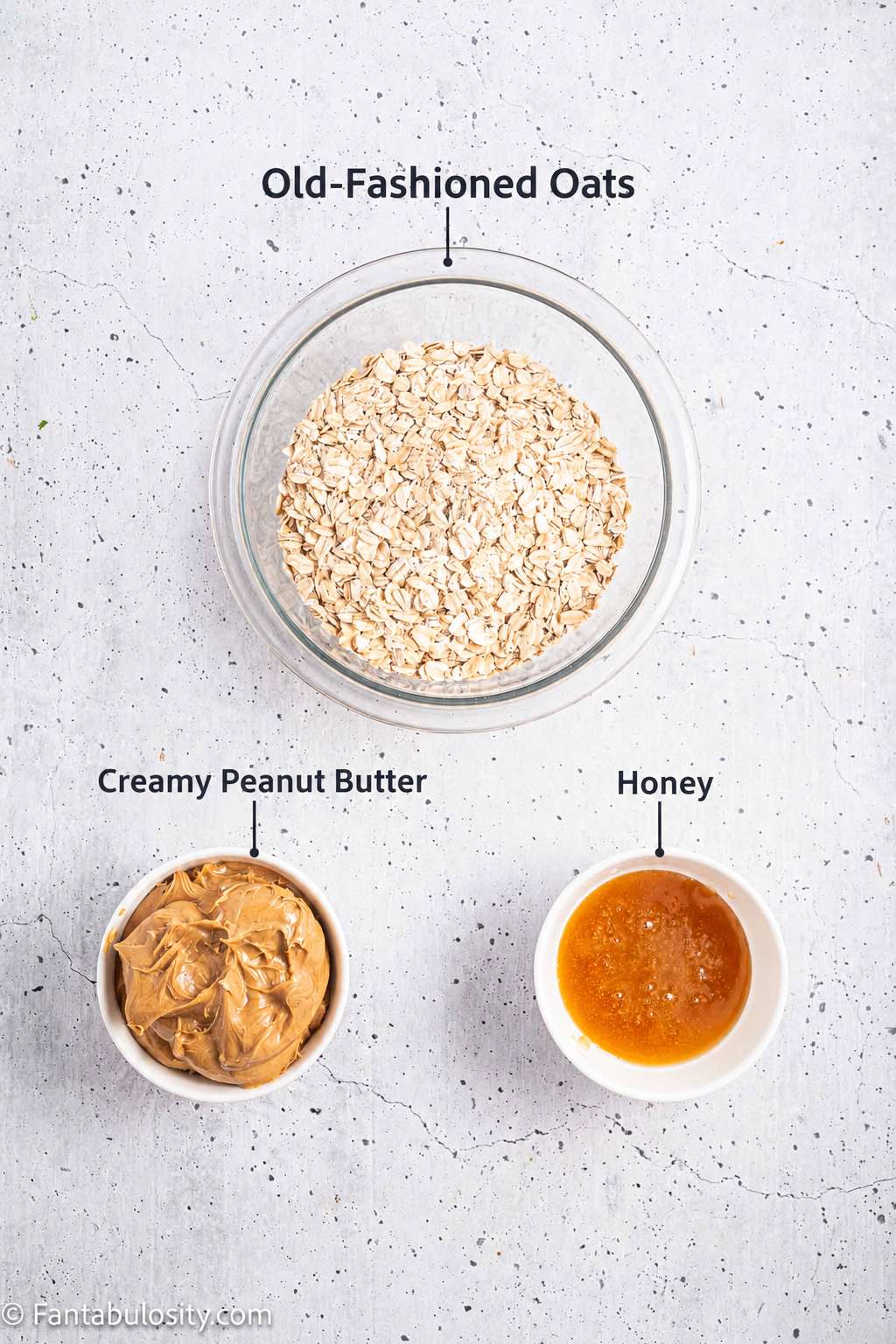 Labeled bowls of old-fashioned oats, creamy peanut butter, and honey for peanut butter oatmeal bars.
