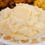 Sour cream mashed potatoes topped with a pat of butter on a floral plate.