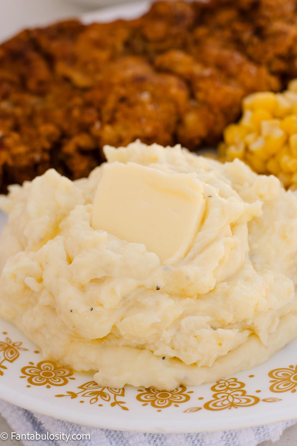 Buttery sour cream mashed potatoes served on a floral plate with dinner.